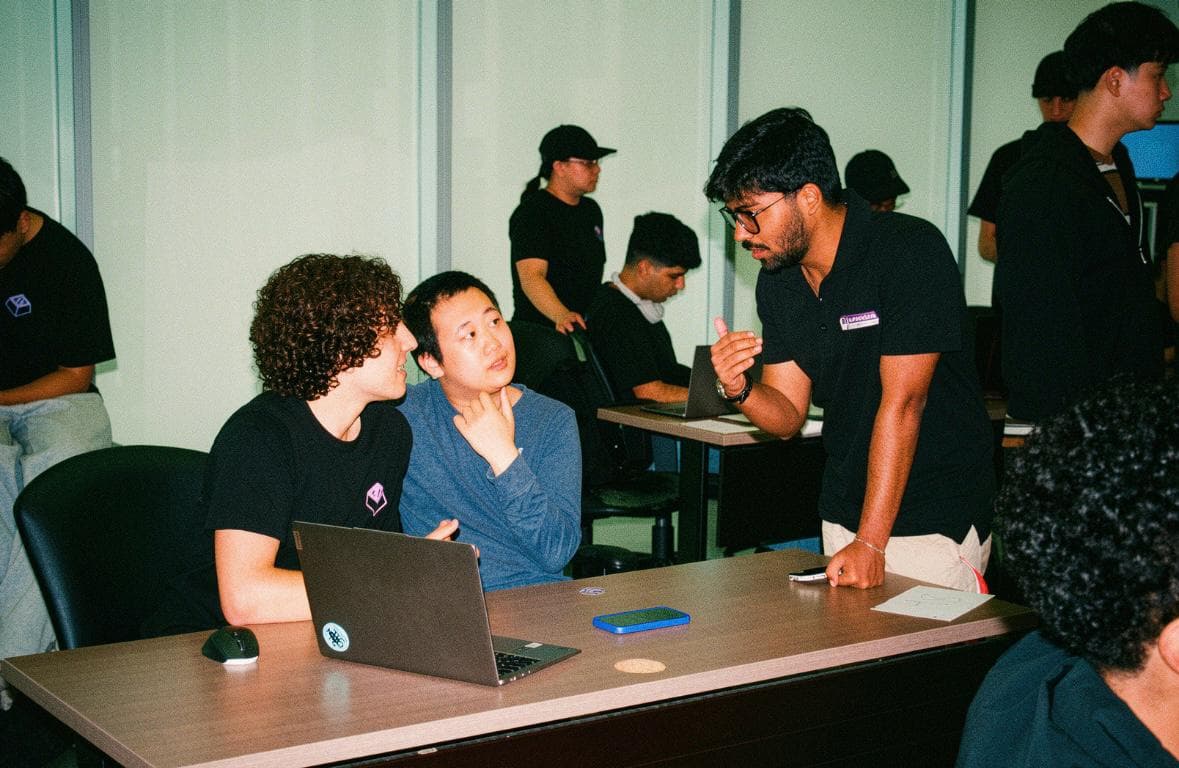 Hackathon participants working on laptops around a table