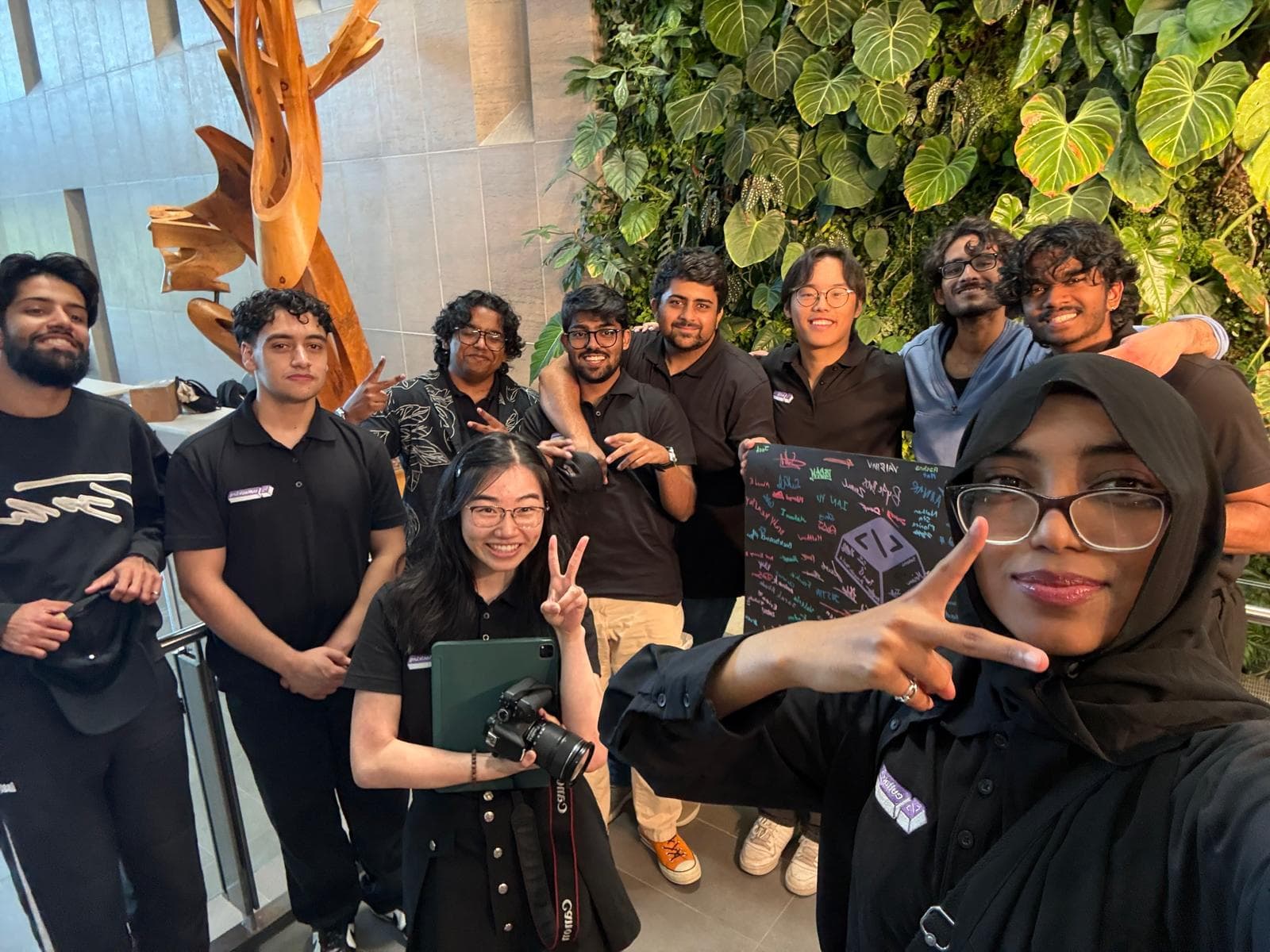 Team in matching black shirts posing for a group photo in an atrium