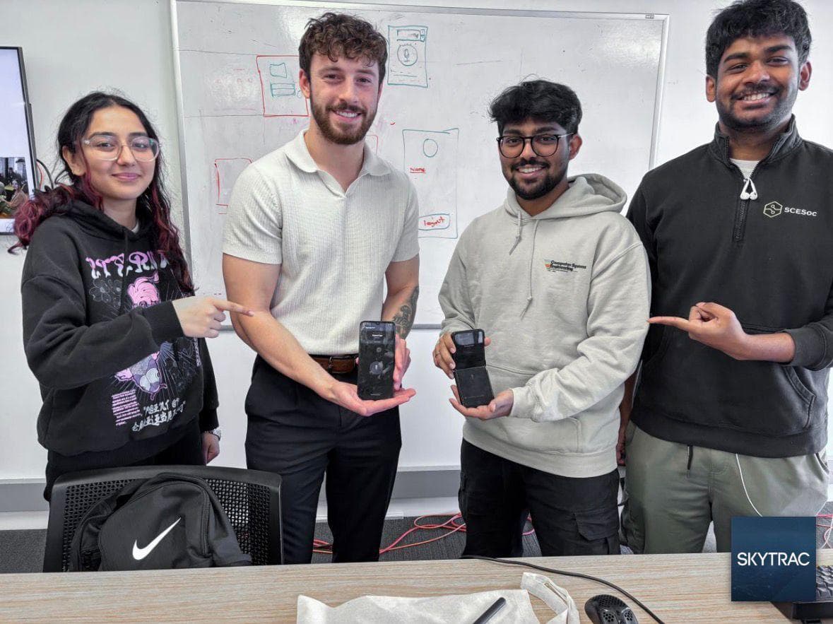 Four teammates holding up phones at the SKYTRAC hackathon